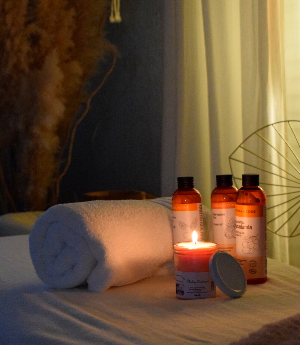 Ambiance cocon d'une séance de massage drainant à domicile — serviette, huiles bio et bougie